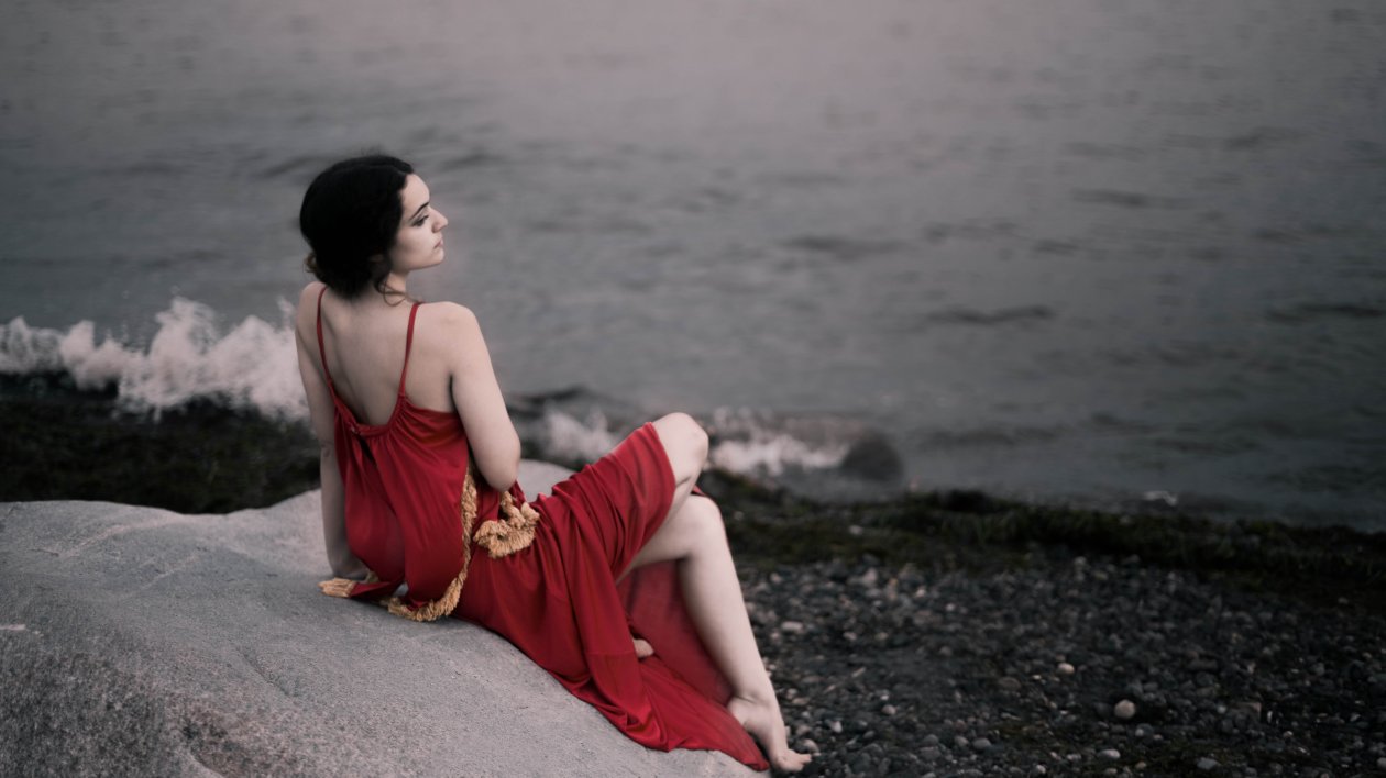 Girl In Red Dress Sitting On Rocks Beach 8k