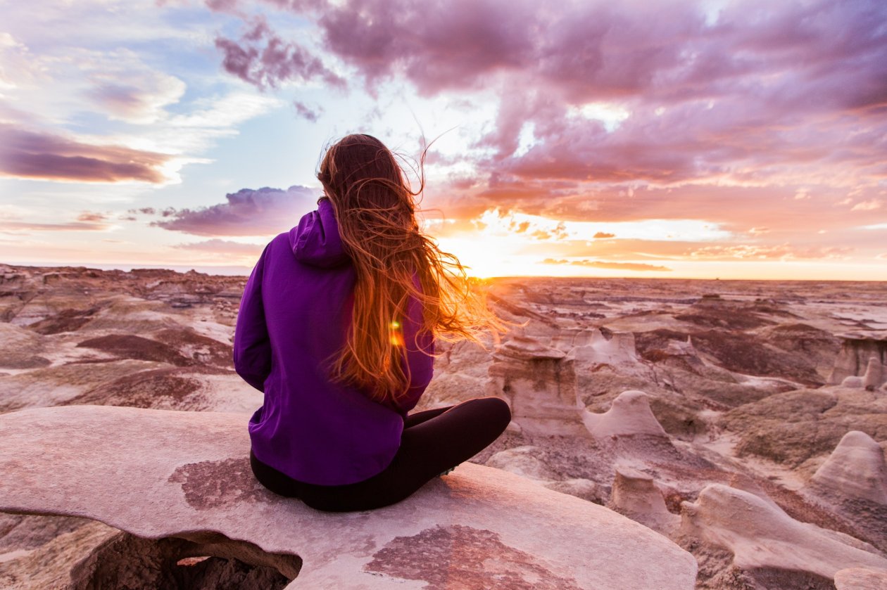 Woman In Hoodie Sitting On Rock Watching Nature
