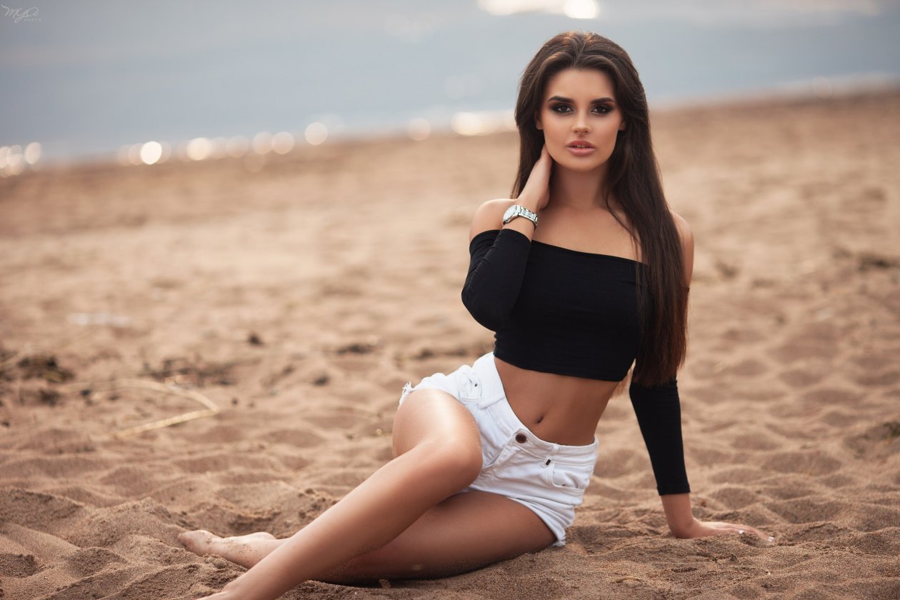Beautiful Brunette Girl Sitting On Sand