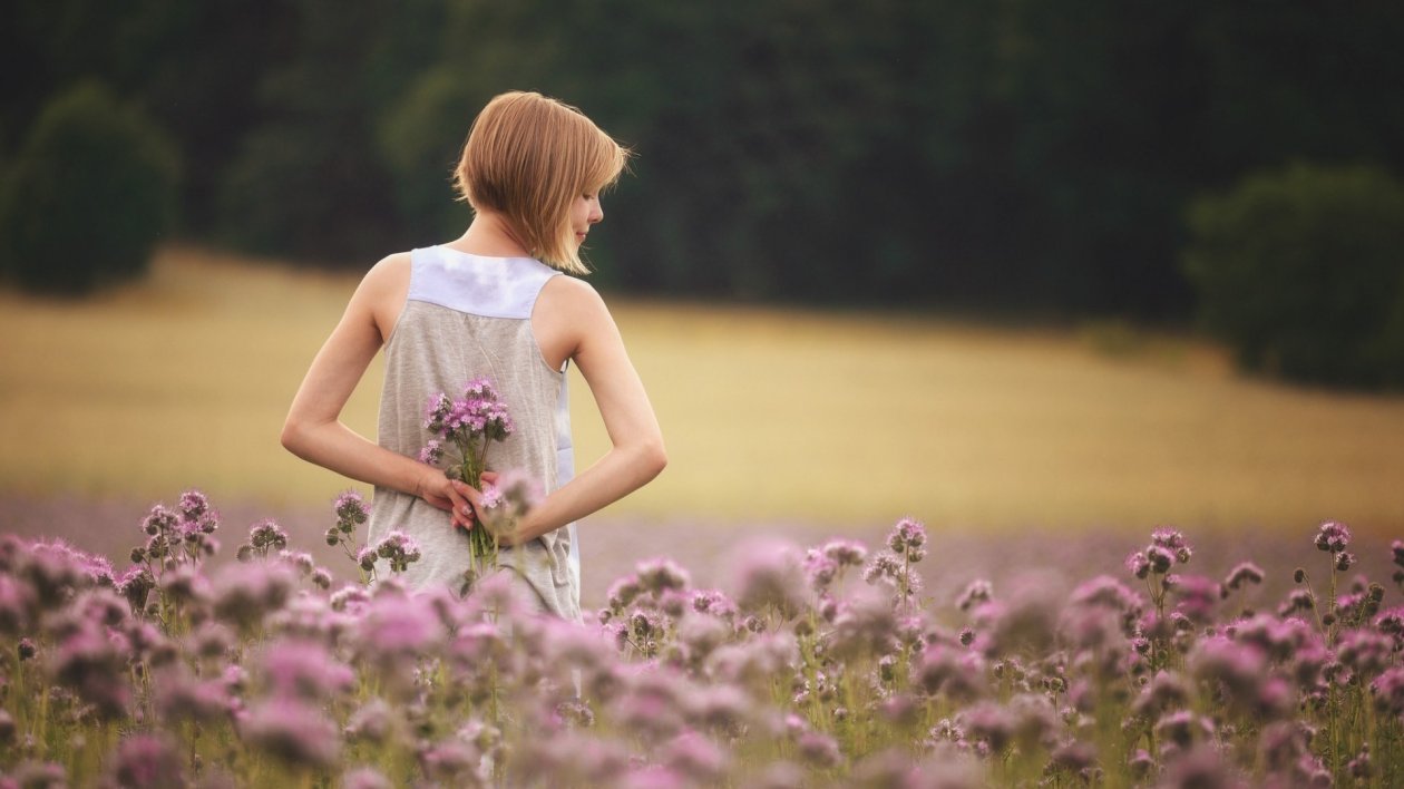 Girl With Flowers Standing In Field