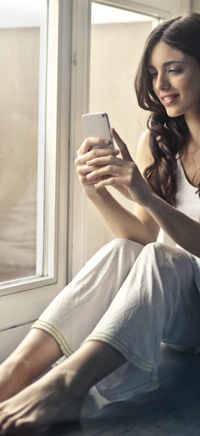 Fond d'écran iPhone Woman Sitting Beside Window Holding Phone