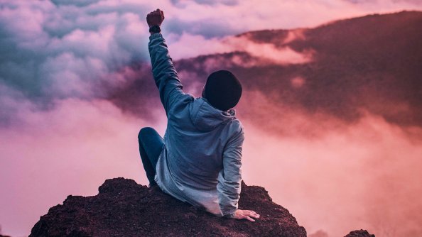 Person Sitting On Rock Looking At Sky