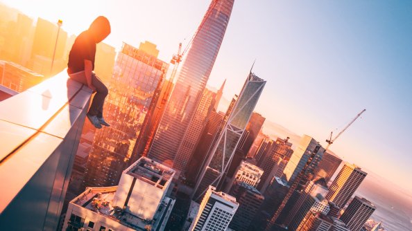 A Person Sitting On The Top Of A Tall Building