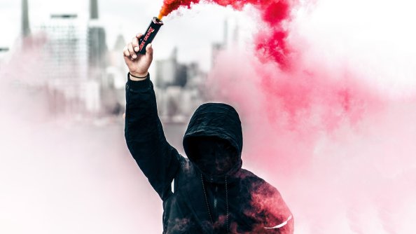 A Person In A Hoodie With Smoke Grenade