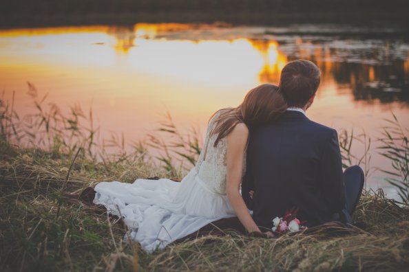 Married Couple Sitting At Lake Watching Sunset