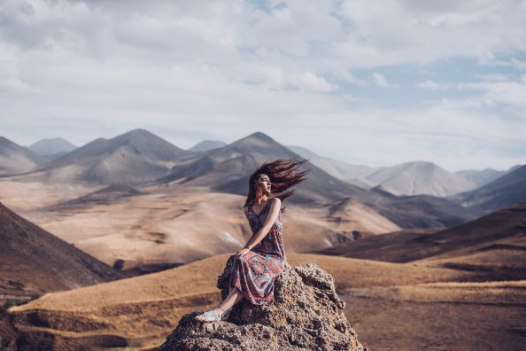 Girl Sitting On Rock Hairs In Air